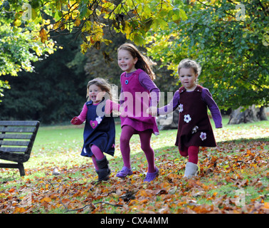 Tre giovani ragazze in esecuzione attraverso foglie autunnali in Hubbard's colline. Foto Stock