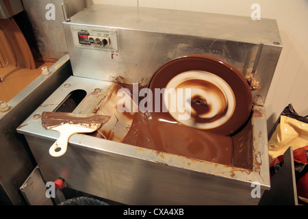 Un cioccolatino la macchina di miscelazione (questo quello utilizzato in un fatto a mano di cioccolato belga shop) in funzionamento in un negozio in Belgio. Foto Stock