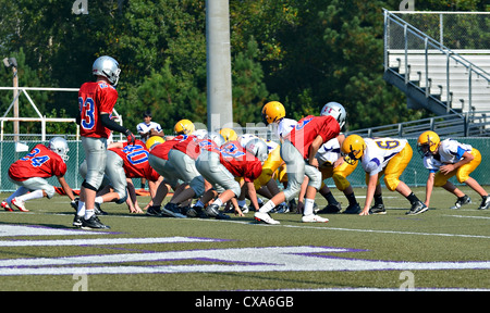 Squadre di 7° grado ragazzi sulla linea pronto per il quarterback per scattare la palla. Foto Stock