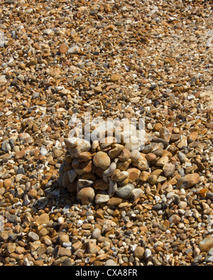 Cumulo di pietre sulla spiaggia circondata da altre pietre creando un'illusione ottica Foto Stock