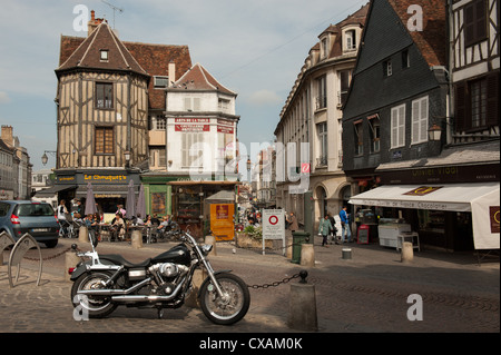 Centro città scena con negozi e caffetterie e Harley Davidson Moto in Auxerre in Francia. Foto Stock