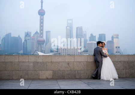 I giovani sposi in posa per le fotografie del vostro matrimonio sul Bund con skyline del distretto finanziario di Pudong Shanghai posteriore Cina Foto Stock