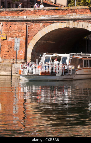 Imbarcazione turistica di uscire dal Canal de Brienne nel fiume Garonne attraverso un rosso arco in mattoni in Toulouse Midi-Pirenei Francia Foto Stock