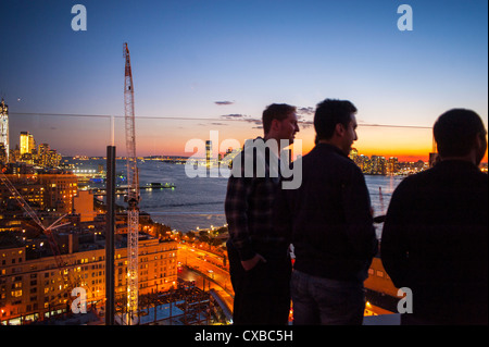 Panoramica degli Stati Uniti, New York City, NY, panoramiche notturne, paesaggio urbano con persone dal Top of the Standard Hotel Bar Rooftop Terrace, Manhattan, gli uomini che condividono bevande a Silhouette, bella notte aerea urbana Foto Stock