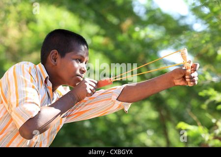 Ragazzo indiano con una fionda nel tentativo di uccidere uccelli Andhra Pradesh in India del Sud Foto Stock