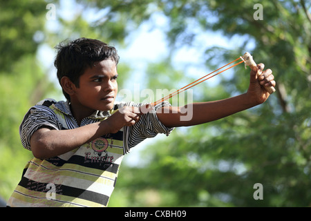 Ragazzo indiano con una fionda nel tentativo di uccidere uccelli Andhra Pradesh in India del Sud Foto Stock