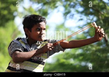 Ragazzo indiano con una fionda nel tentativo di uccidere uccelli Andhra Pradesh in India del Sud Foto Stock