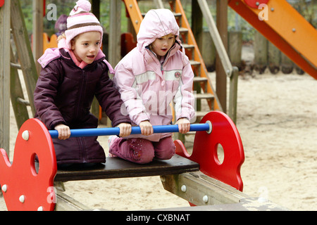 Berlino, ragazze bounce su un bambino su un parco giochi altalena Foto Stock
