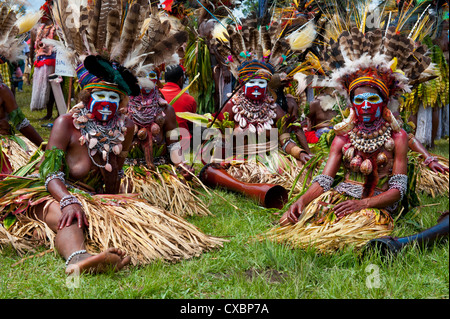 Vestiti in maniera colorata e il volto dipinto di tribù locali per celebrare il tradizionale cantare cantare nelle Highlands di Papua Nuova Guinea Foto Stock