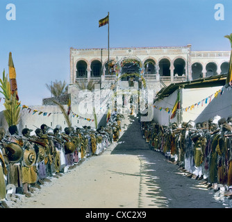 Vista colorata di capi e dignitari, con scudi e fucili, che costeggiano l'ingresso al luogo della cerimonia di incoronazione per l'imperatore etiope Haile Selassie i, Addis Abeba, Etiopia, 1930. (Foto di Burton Holmes) Foto Stock