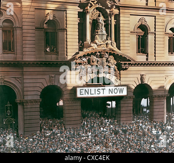 Vista colorata di una folla riunita a Martin Place per un raduno di reclutamento della prima guerra mondiale, Sydney, Australia, 1917. Un cartello con la scritta ‘enlist Now’ è appeso fuori   entrata principale dell’Ufficio postale Generale. (Foto di Burton Holmes) Foto Stock