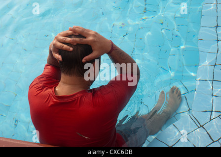 Uomo che indossa una T-shirt rossa in una piscina. Si tratta di una piscina all'aperto, non riscaldata, e l'acqua fredda. Foto Stock