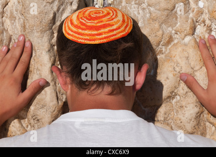 Chiusura del giovane uomo con luminosi yarmulka pregando presso il Muro Occidentale, la Città Vecchia di Gerusalemme, Israele, Medio Oriente Foto Stock