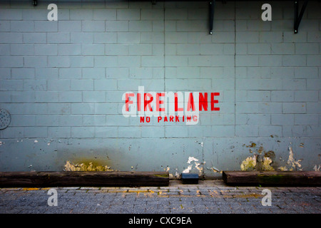 Grungy muro di mattoni con colore rosso brillante parole indicanti Fire Lane n. Parcheggio. Buona per sfondo Foto Stock