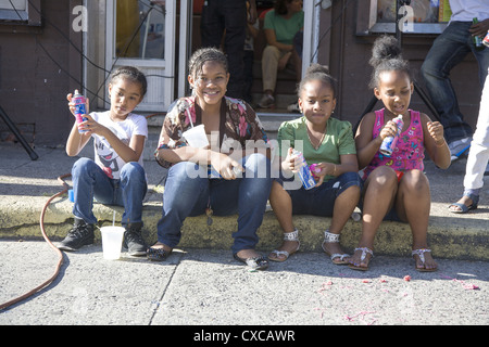 I bambini seduti sul cordolo su Cortelyou Rd. a Flatbush Frolic Street Festival di Brooklyn, New York. Foto Stock