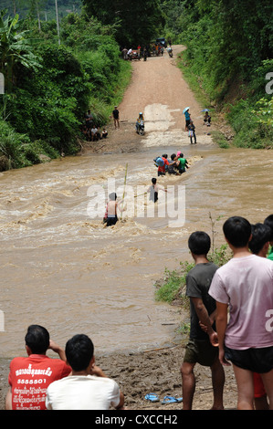 Gli abitanti di un villaggio di lotta attraverso il fiume allagata nel villaggio Banthapho, Luang Prabang, Laos. Foto Stock