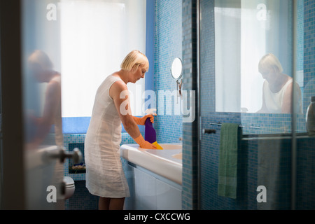 Donna matura bagno di pulizia con detergente spray Foto Stock