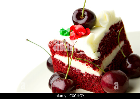 Delizioso velluto rosso layer cake con glassa bianca guarnita con ciliegie fresche contro uno sfondo bianco. Foto Stock