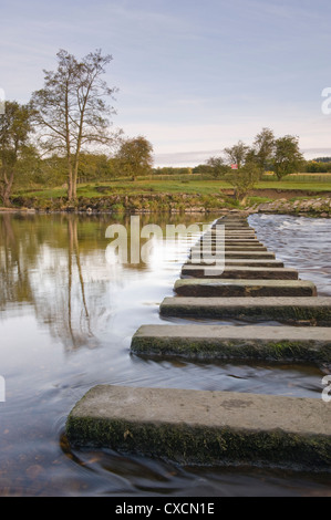 Basso punto di vista ravvicinata di calma acqua fluente round pietre miliari attraversando SCENIC RIVER - Fiume Wharfe, Burley in Wharfedale, nello Yorkshire, Inghilterra, Regno Unito. Foto Stock