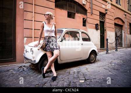 Donna in piedi accanto alla Fiat 500 per le strade di Roma, Roma, Italia, Italia, Europa Foto Stock