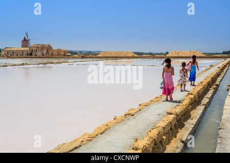 Le tre ragazze a piedi lungo le saline in Laguna dello Stagnone vicino Trapani, Sicilia, Italia Foto Stock