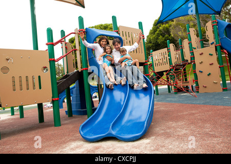 Famiglia scivolare giù scorrere sul parco giochi Foto Stock