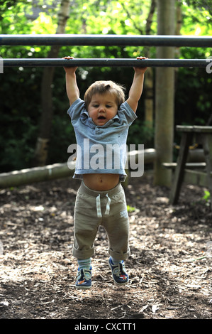 Un bambino dall'aspetto duro appeso al bar. Bambini bambini che giocano nell'area giochi Gran Bretagna UK Foto Stock
