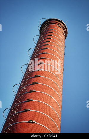 Ciminiera di una fabbrica contro il cielo blu Foto Stock