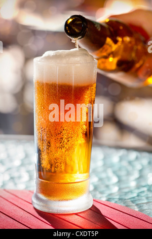 Versare la birra in tazza dalla bottiglia Foto Stock