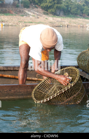 Pescatore in barca in legno, lavando il suo cocco e pesca di bambù pentole, Fiume Mahanadi, Orissa, India, Asia Foto Stock