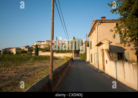 Vigneti ai piedi del borgo fortificato medievale di Sablet nella Vaucluse Francia meridionale, immerso nella luce del sole serale Foto Stock