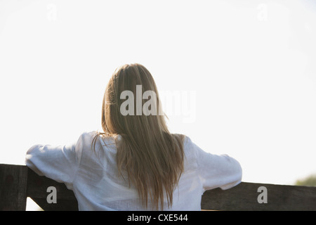 Donna appoggiata contro la ringhiera, vista posteriore Foto Stock