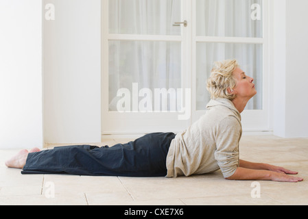 Donna matura facendo cobra posano con gli occhi chiusi Foto Stock