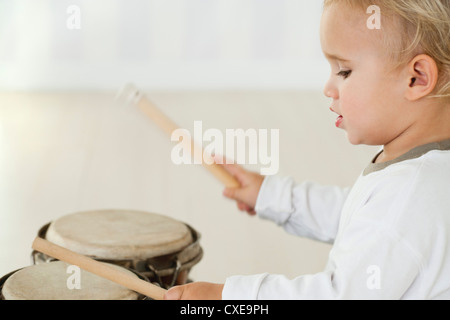 Baby boy suonando la batteria, vista laterale Foto Stock