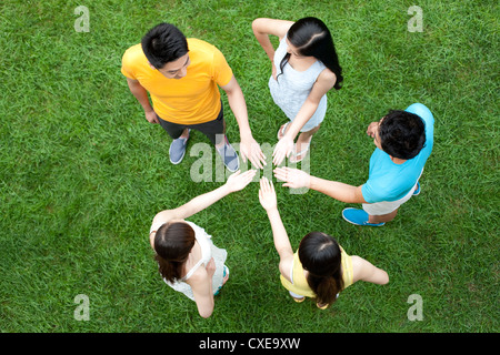 Gli amici mettendo le mani insieme sul prato Foto Stock