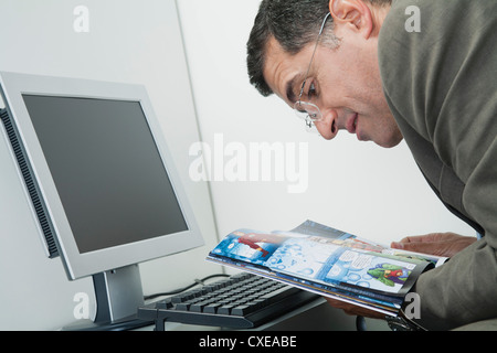 Uomo maturo la lettura del libro di fumetti a scrivania in ufficio Foto Stock