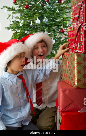 Ragazzi cercando eccitato a pila di regali di Natale Foto Stock