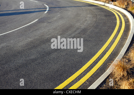 Double yellow lines and a curve in road Foto Stock