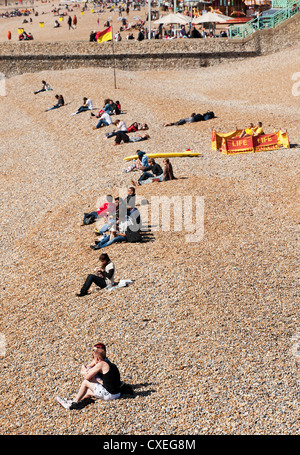 La gente seduta sulla spiaggia di Brighton Foto Stock