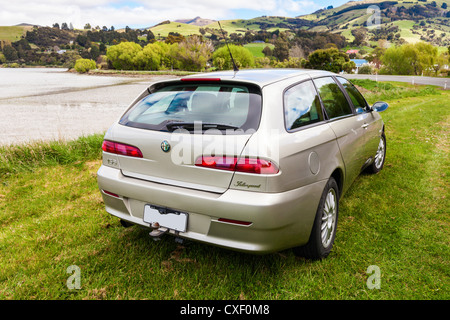 Color Champagne l'Alfa Romeo 156 Sportwagon, parcheggiata accanto al porto di Akaroa in Nuova Zelanda. Foto Stock