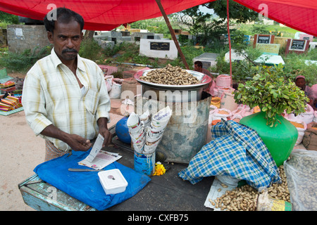 Indian uomo vendita arachidi cotti al vapore in un mercato indiano. Andhra Pradesh, India Foto Stock