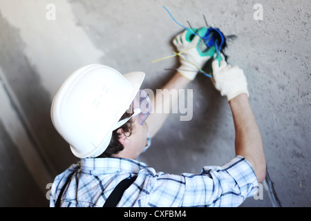 Lavoratore mette i fili nella parete Foto Stock