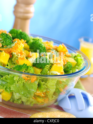 Broccoli-mango--carota insalata di lattuga in una ciotola di vetro con insalata di server Foto Stock