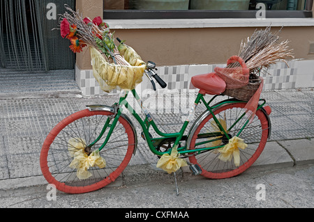 Donna bike stop sul marciapiede della mostra street e fregio decorato con fiori Foto Stock