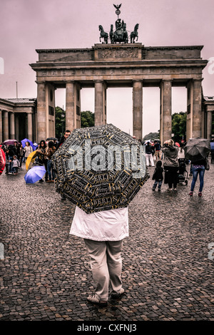 Donna in piedi con un souvenir ombrello di Berlino vicino alla Porta di Brandeburgo Foto Stock