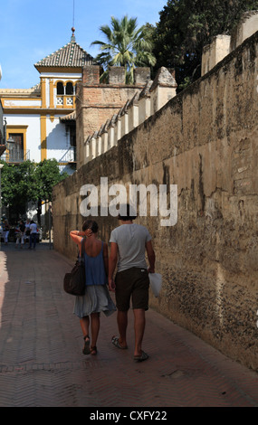 Coppia giovane camminando in la Juderia vecchia parte ebraica di Siviglia turistica lungo la parete di Alcazar Foto Stock