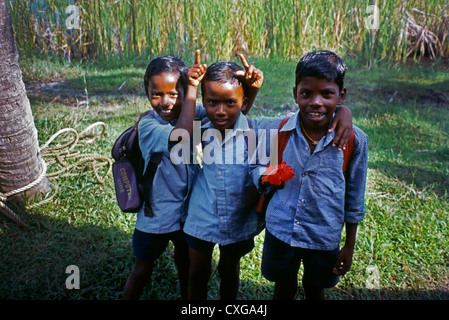 India Kerala Backwaters scuola i ragazzi in uniforme di un ragazzo azienda fiore Foto Stock