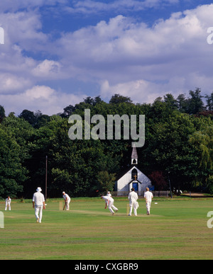 Cricket sul villaggio verde con St.George's Chiesa al di là. Il West End, vicino Esher Surrey, Inghilterra. Foto Stock