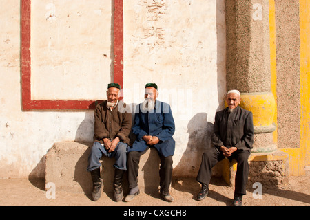 Uighur uomini siedono al di fuori di una moschea in un villaggio ai piedi delle Montagne in fiamme ad est di Turpan, Xinjiang, Cina Foto Stock
