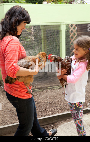 Una madre e figlia sono nel cortile tenendo i loro polli. Foto Stock